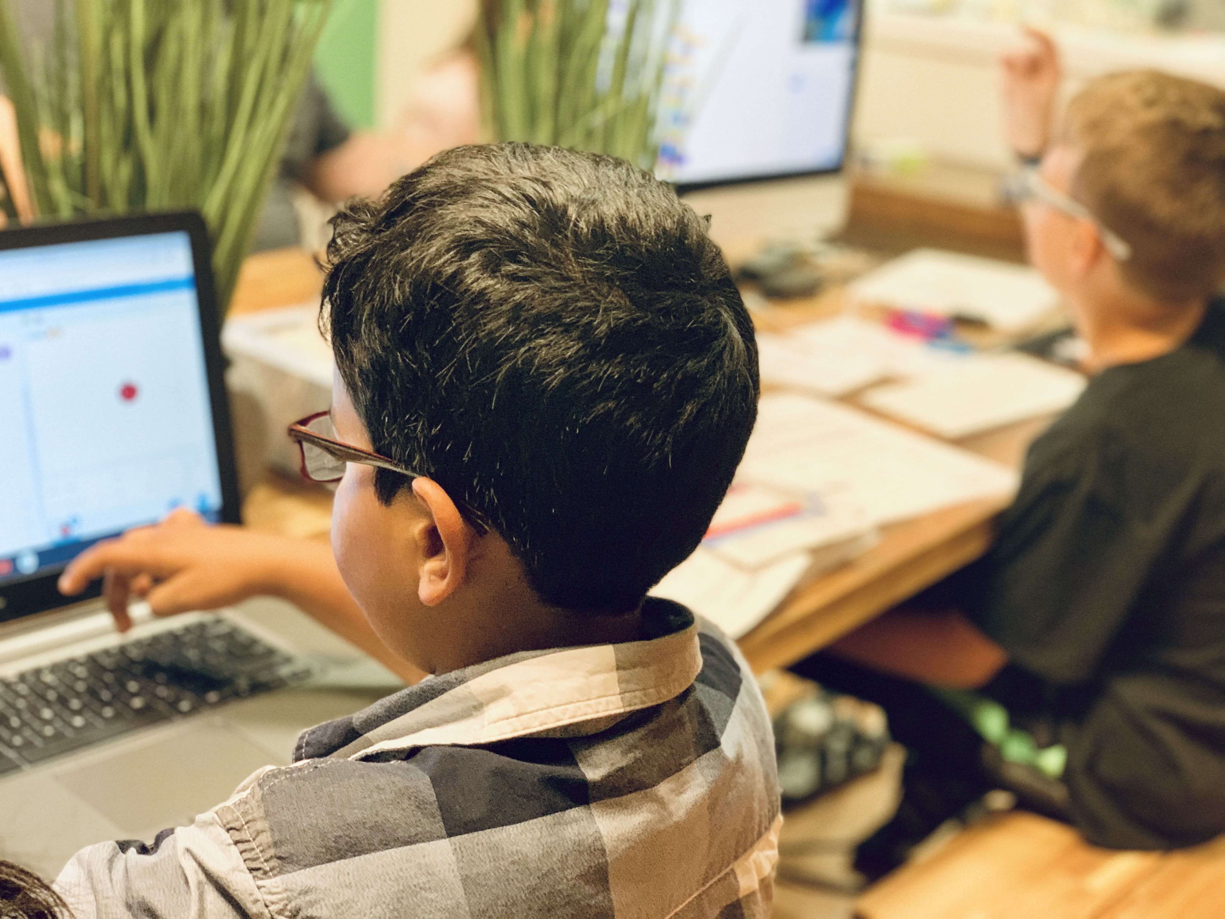 Two boys studying on a laptop and desktop